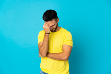 Young caucasian man isolated on blue background with headache