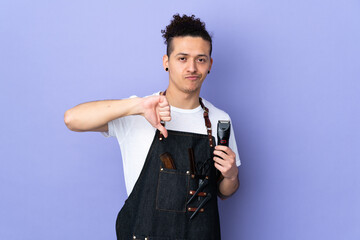 Barber man in an apron over isolated purple background showing thumb down sign
