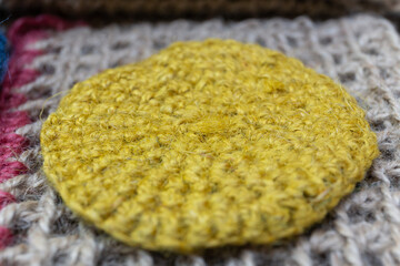 A knitted jute product in the form of a yellow round rug lies on a jute background of natural wood.