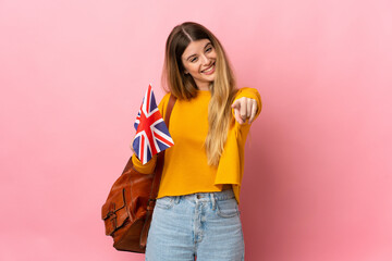 Young blonde woman holding an United Kingdom flag isolated on white background pointing front with...