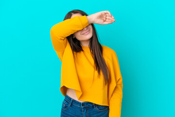 Young Ukrainian woman isolated on blue background covering eyes by hands