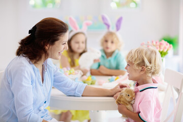 Mother and kids, family coloring Easter eggs.