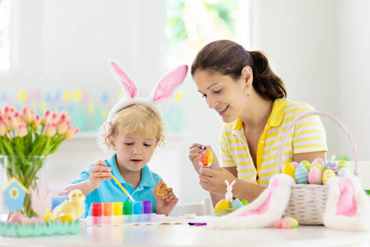 Mother and kids, family coloring Easter eggs.