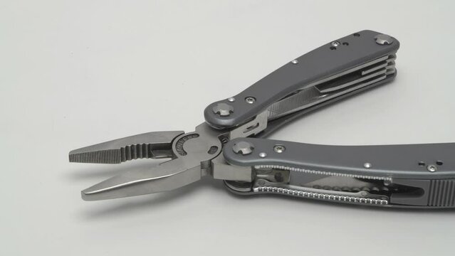 Slow motion panorama of a multitool on a white background.