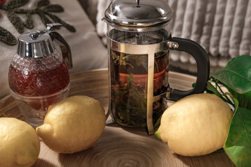 herbal tea in metal glass french press served with fresh lemon fruits , honey on wooden green tray...