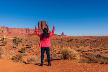 Fototapeta na wymiar A tourist woman enjoys view of West Mitten Butte in Monument Valley. Travel in the winter in Arizona, USA