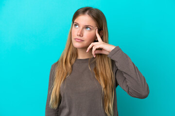 Young blonde woman isolated on blue background making the gesture of madness putting finger on the...