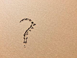 A sandy surface bears a clear question mark, indicating a query or doubt.