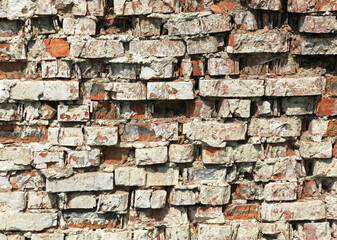 Old brick wall, texture, background. Chipped and crumbling wall, made of old red bricks, darkened by old age. Ancient vintage brickwork.  Background and backdrop of structural masonry of old building