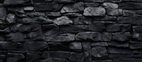 A close-up black and white photograph showcasing the intricate patterns and textures of a stone wall. The contrast between dark and light areas creates a visually striking abstract composition.