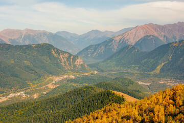 mountains, sky and green and yellow forest in valley. Place for trekking tourism