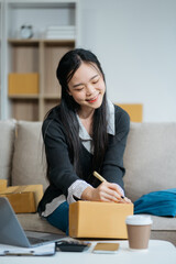 Portrait young attractive asian female owner startup business work happy with box at home prepare parcel delivery in sme supply chain, start up small business concept.