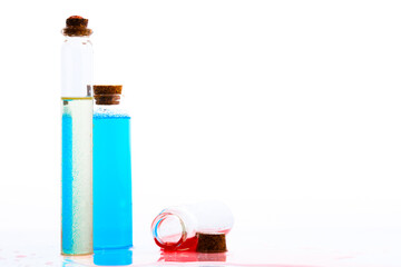 Two glass bottles filled colorful liquids and one bottle filled over the ground on a isolated white background