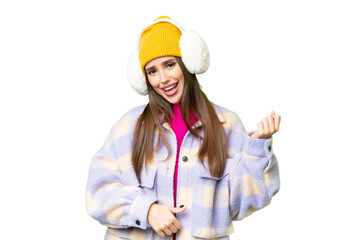 Young woman wearing winter muffs over isolated chroma key background making guitar gesture