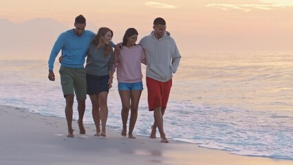 Young couple with friends wearing casual clothing hugging as they walk towards camera along beach at dawn - shot in slow motion - Powered by Adobe