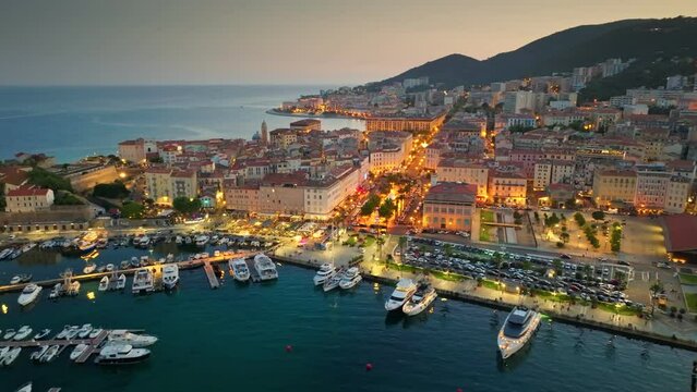 Aerial evening shot of Ajaccio old town, Corsica island. Flying over harbor, old houses and city lights in Ajaccio - capital of Corsica, France. UHD, 4K 