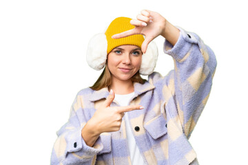 Young blonde woman wearing winter muffs over isolated chroma key background focusing face. Framing...