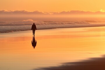 A person is walking on the beach at sunset