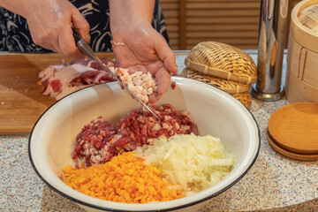 Cook pours finely chopped meat from a knife into a bowl with chopped onions and pumpkin to prepare minced meat.