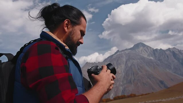 A young male photographer in the mountains takes pictures of the landscape