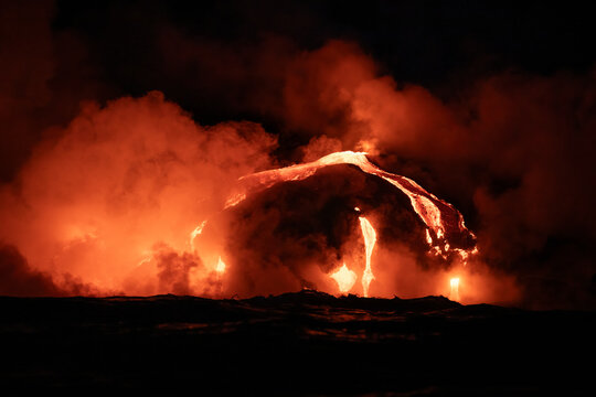 Red hot lava from the volcano in Hawaii frowing into the sea at night