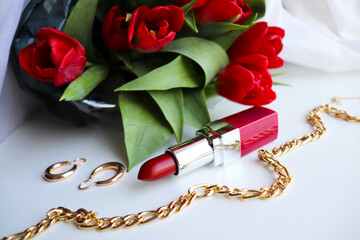 red lipstick and bouquet of flowers on white background