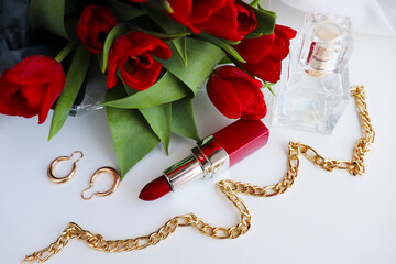 red lipstick and bouquet of flowers on white background