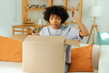 Unhappy african woman unpack delivered box receiving damaged shipping problem in postal service....