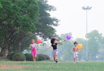 Group of diverse siblings or friends boy and girls exercise in park with colorful balloons, joyful...