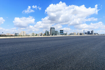 Asphalt highway road and modern city skyline under blue sky