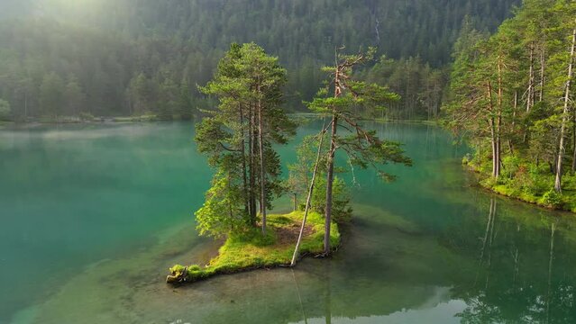 Beautiful lake Fernsteinsee with morning fog in the mountains. Small island with trees in alpine lake. Austria, Tyrol alpine nature. Aerial shot