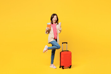 Traveler woman wear casual clothes hold passport ticket bag do winner gesture isolated on plain...
