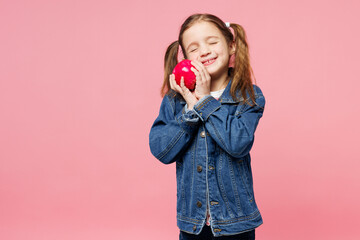 Little child smiling cute kid girl 7-8 years old wears denim shirt have fun hold in hand hug tasty red apple isolated on plain pastel light pink background. Mother's Day love family lifestyle concept.