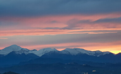 Tramonto arancio sopra le cime dei monti innevate