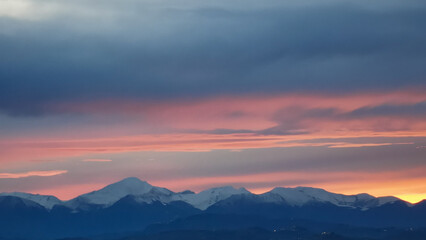Tramonto arancio sopra le cime dei monti innevate