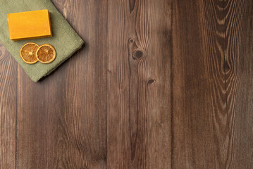 A piece of soap and dried lemon on a towel on a wooden background. Spa concept