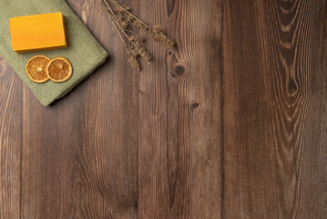 A piece of soap and dried lemon on a towel on a wooden background. Spa concept