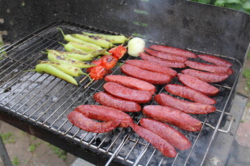 delicious grilled sausage cooked on the barbecue. tomatoes and peppers.Barbeque grate diet concept closeup. Delicious picnic party background.