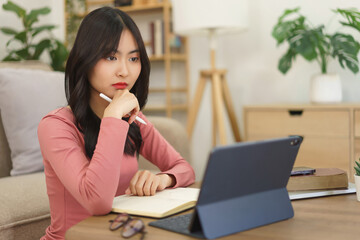 Young businesswoman holding pen stylus and concentrated with reading business report on tablet