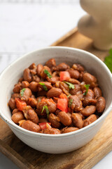 Food dish made of beans, tomatoes, and cilantro on a wooden table