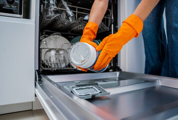 Woman adding detergent to dishwasher machine drawer