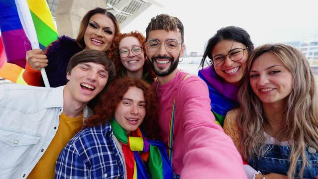 Young group of friends with rainbow flags celebrating gay pride day festival together. LGBT community people concept.
