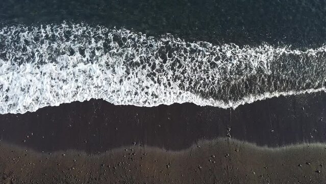Wellen am schwarzen Strand von Amed, Karangasem, Bali, Indonesien