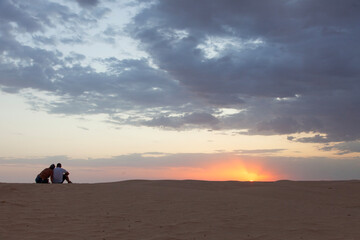 ouple looking at the sunset over the sand dunes at the Sahara desert - 754850533