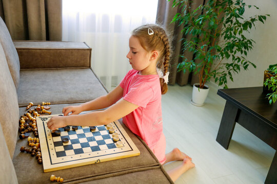 little girl at home playing with checkers and chess pieces