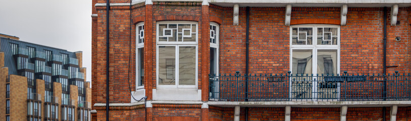 balcony with classic white windows from typical London architecture with red brick wall, panoramic banner