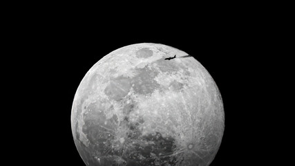 the moon rises against a deep black sky and an airplane flies by with a streak of condensation