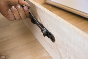 Hand assembly of new furniture by an individual using both specialized and homemade tools. Using furniture fittings during the assembly process.