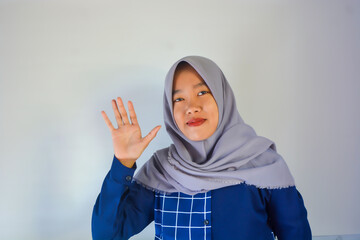 Young asian woman wearing blue shirt with gray hijab makes hand refusal gesture, saying no...