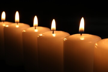 Burning candles on dark background, closeup. Memory day